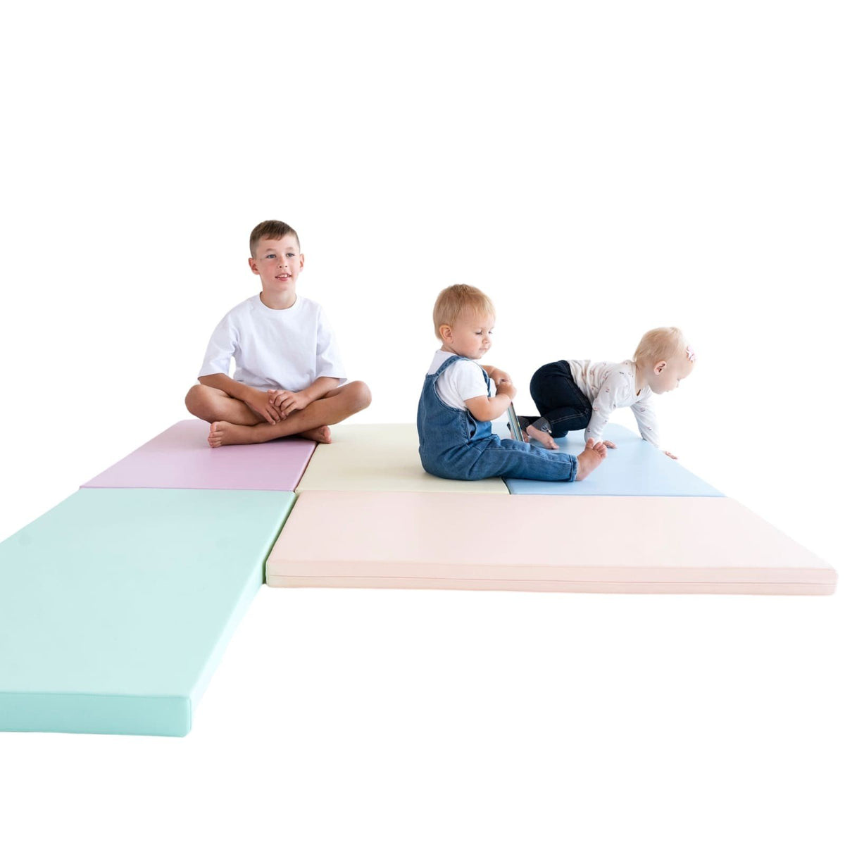 8. Three children playing on pastel mats, showcasing social interaction and developmental play