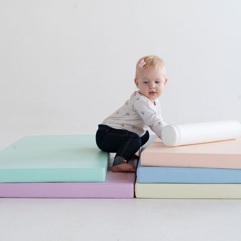 5. Toddler climbing pastel-colored mats, demonstrating motor skill development and exploration