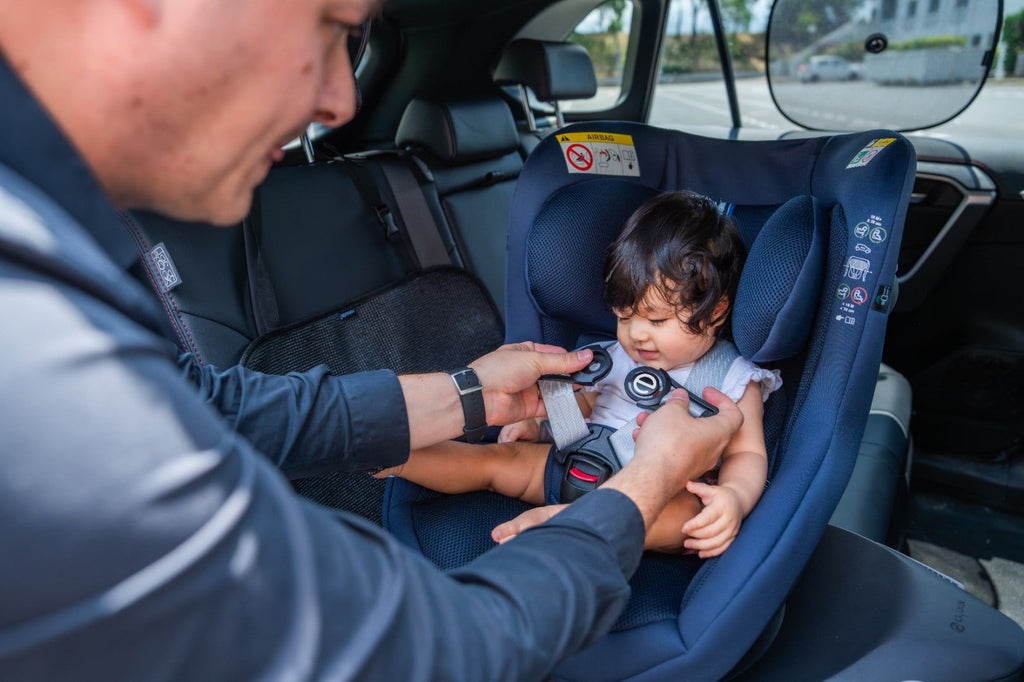 2. Adult adjusting Ezimoov safety clip on child's car seat harness for secure fit