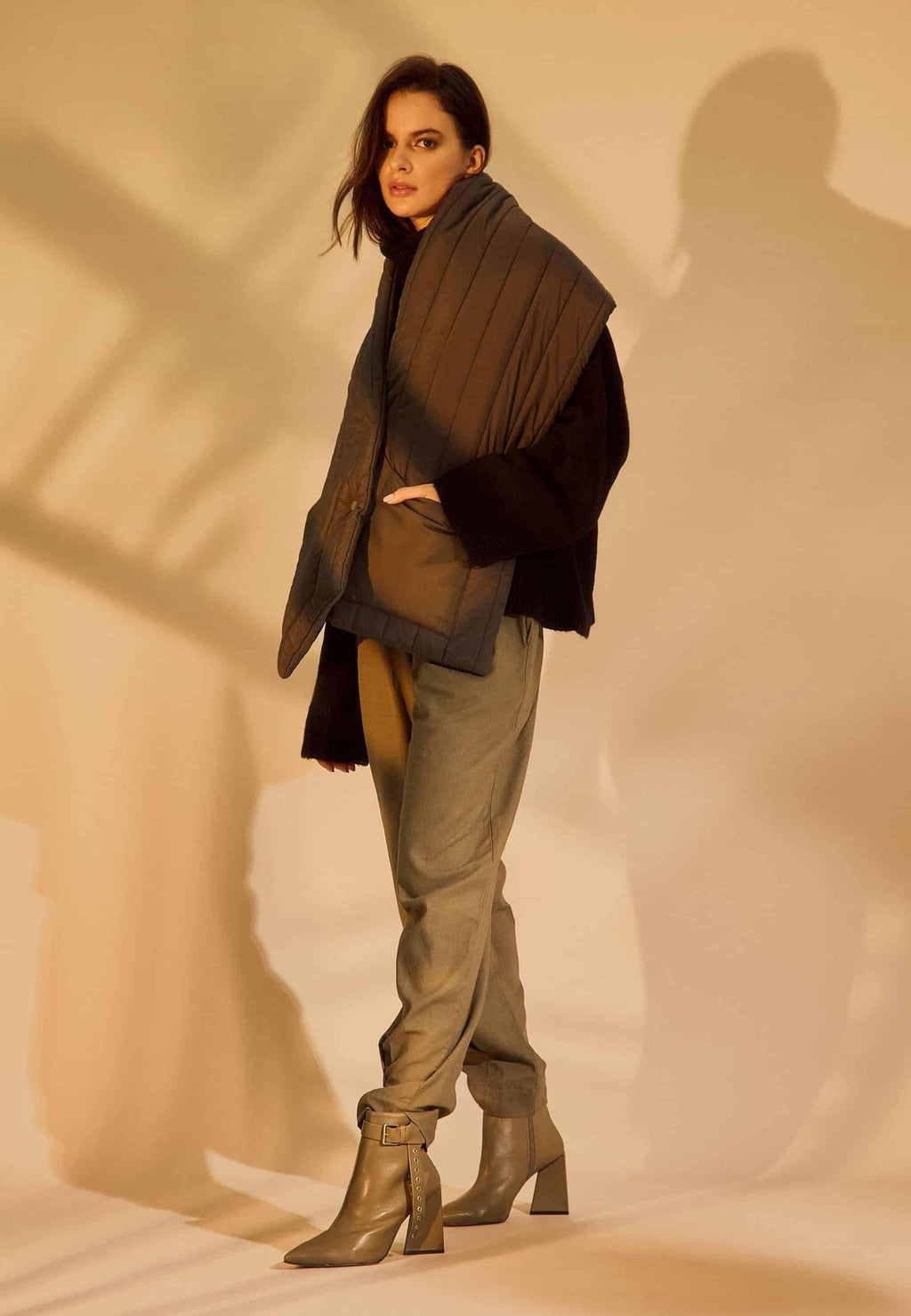 2. Woman wearing salvia green leather ankle boots with pointed toe and side buckle, styled with casual pants in warm lighting