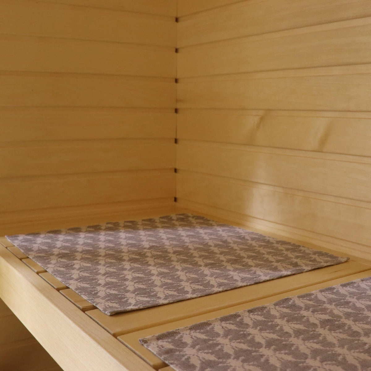 2. Two sauna bench seating pads with Hiiumaa fly pattern on wooden sauna bench
