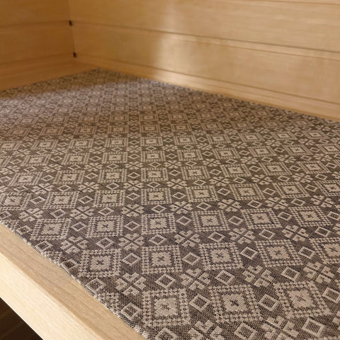 1. Sauna bench seating pad with traditional Tartu County mitten pattern in grey and white, made of linen and cotton, placed on wooden sauna bench.