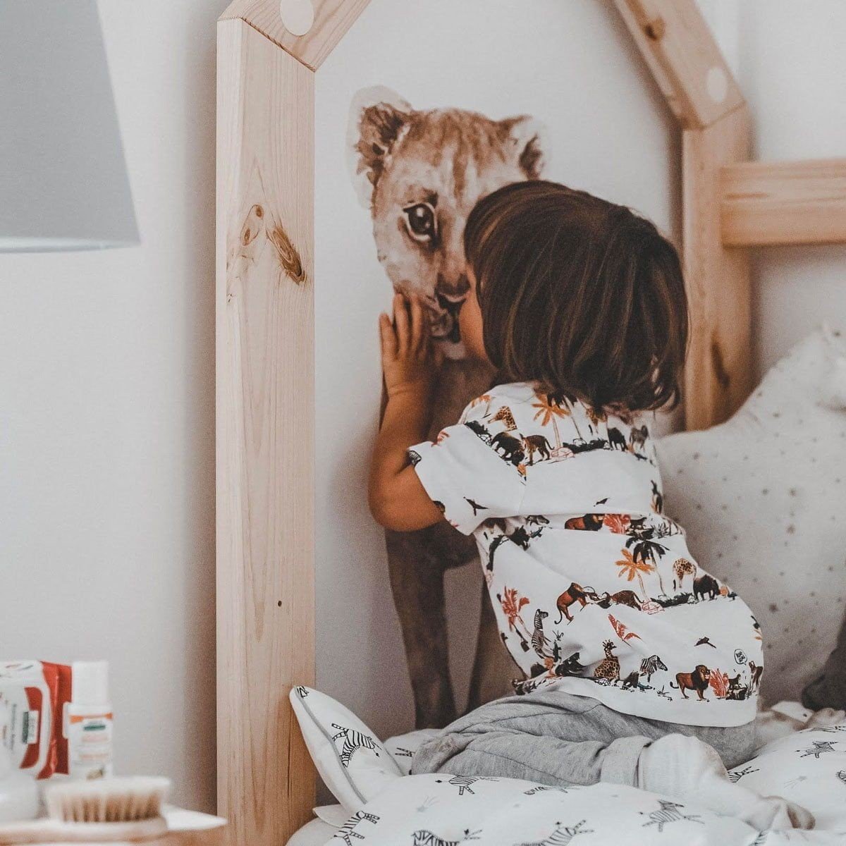 4. Child interacting with Savanna Wonderland wallsticker of lion cub on wooden bed frame