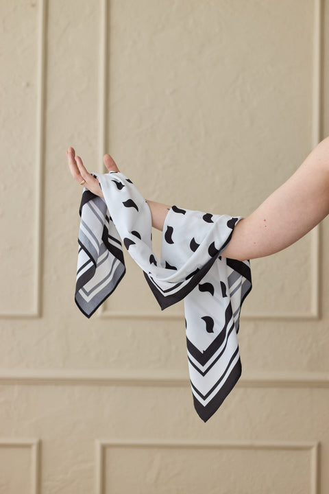 1. Women's Garbanota Scarf Black Birds draped elegantly on arm, showcasing silky texture and black bird pattern