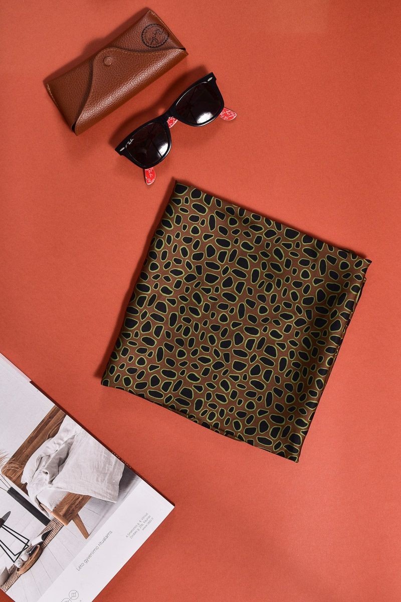 2. Flat lay of Garbanota Scarf Curly Little Leopard with sunglasses and leather case on orange background