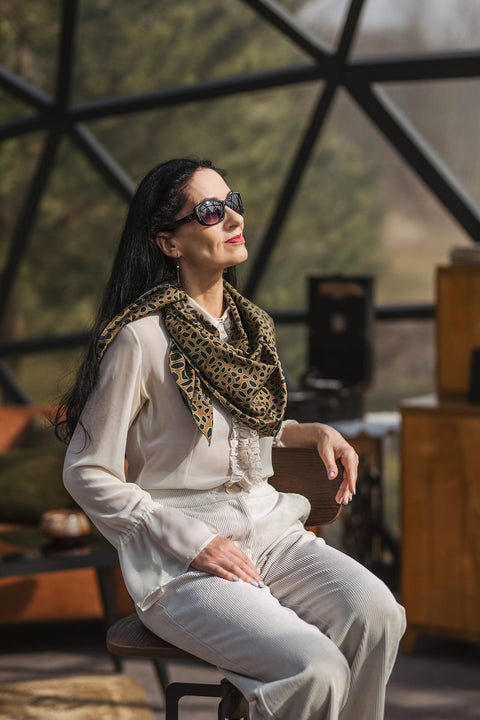 1. Woman wearing Garbanota Scarf Curly Little Leopard in lifestyle setting, showcasing elegant styling