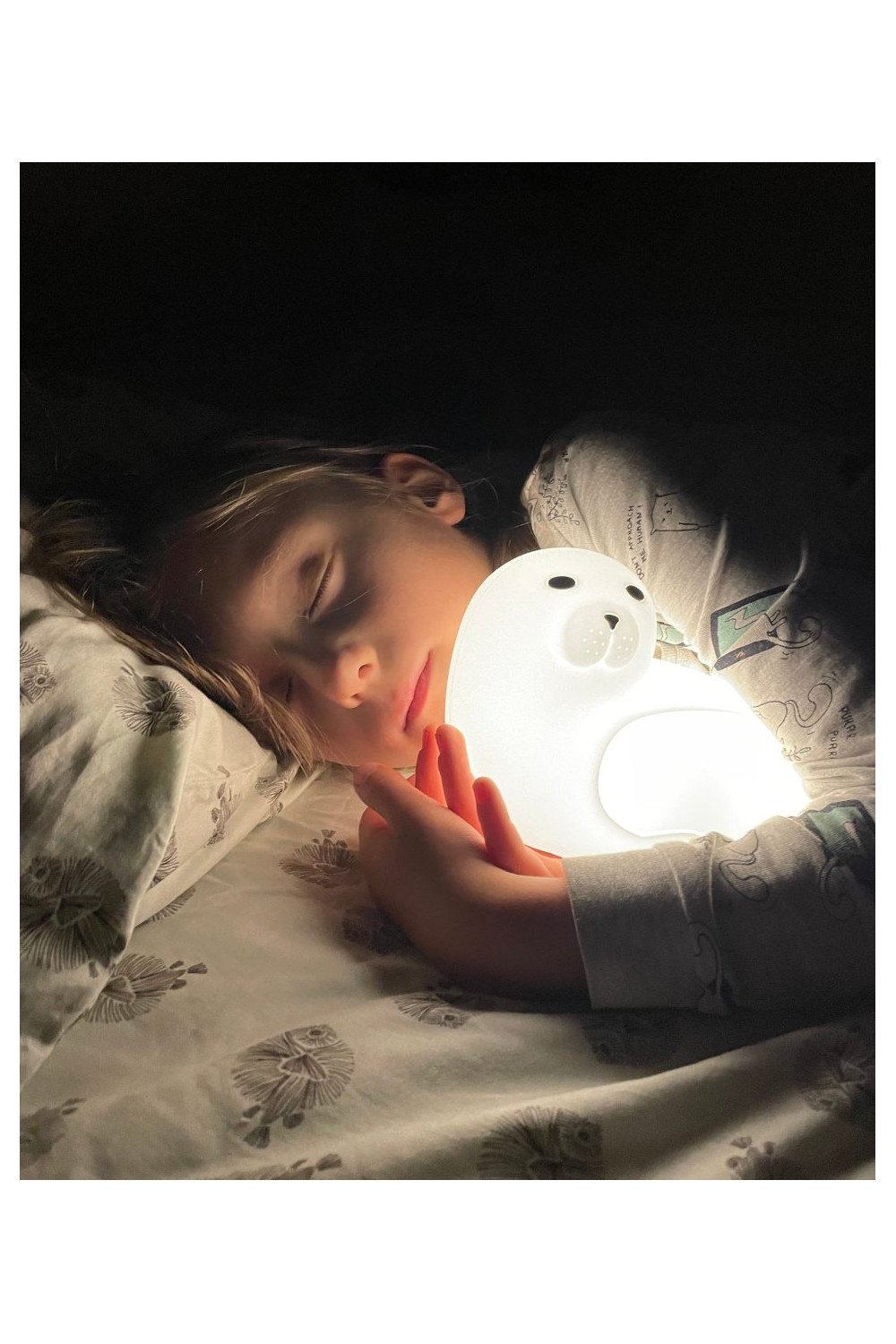 1. Child sleeping while hugging glowing white seal-shaped lamp