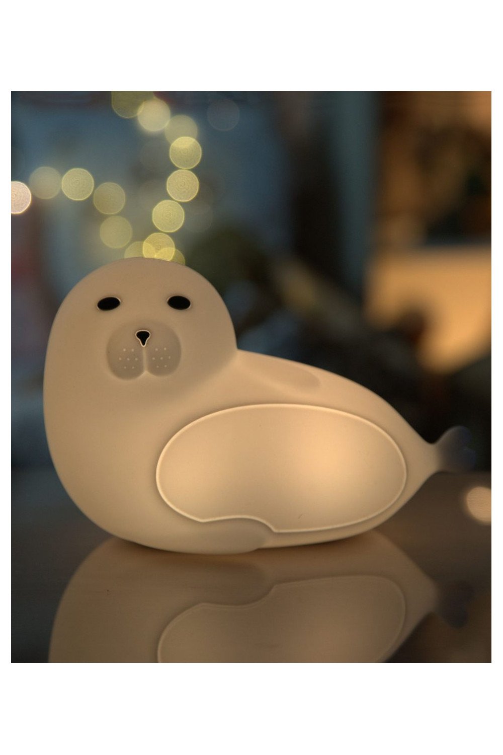 3. Glowing white seal-shaped lamp in dimly lit room with bokeh lights