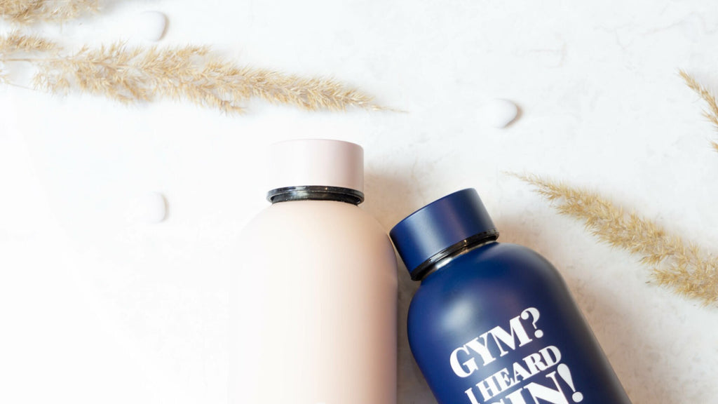 1. SEIK dark blue water bottle with 'Gym? I Heard Gin!' slogan, shown with beige bottle on marble surface