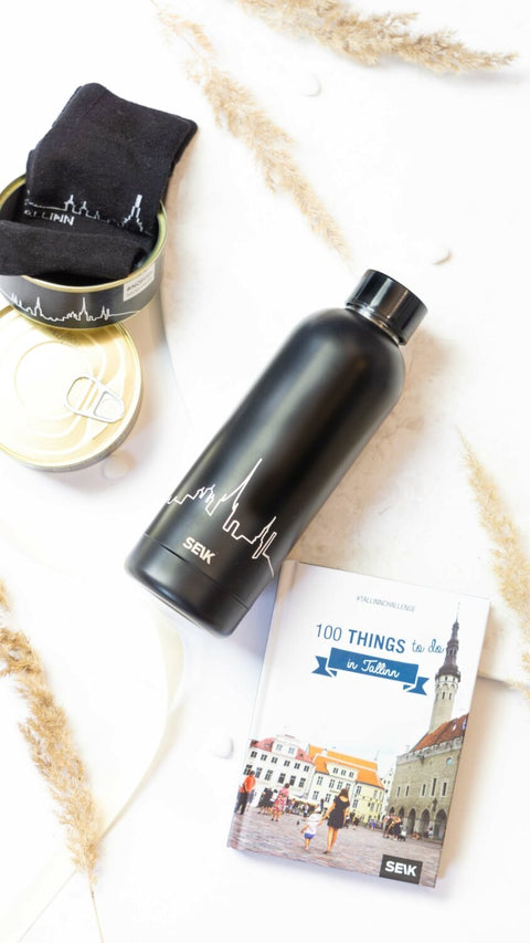 2. SEIK black thermos with Tallinn skyline, displayed with a book and accessories on a white surface