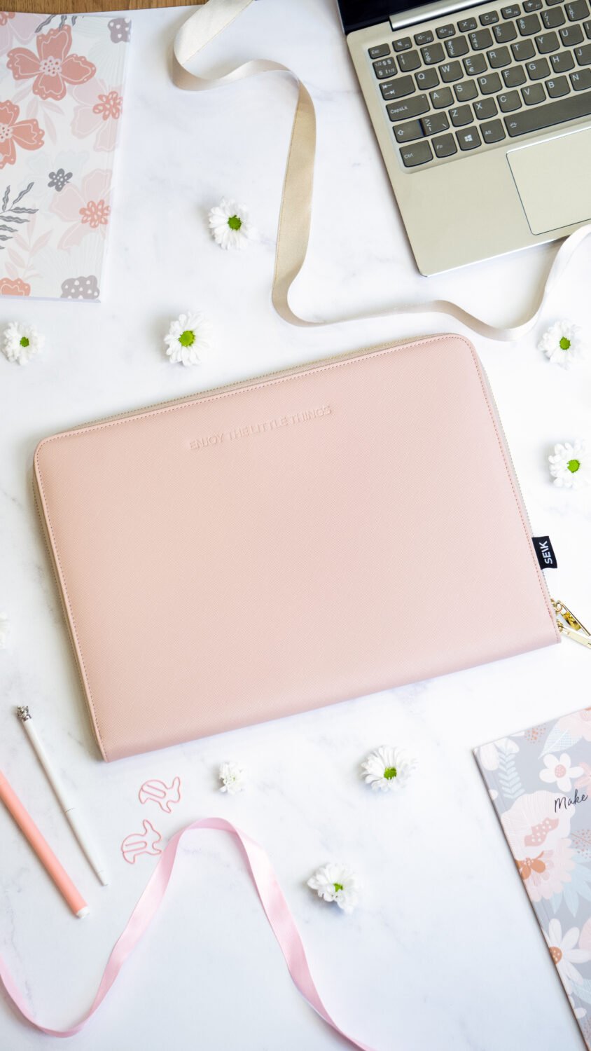 1. SEIK pink laptop sleeve on a desk with floral decor, showcasing minimalist design