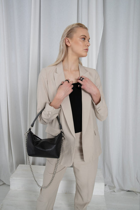 2. Woman wearing PYKOK Soft Leather Baguette Handbag Selena with chain, styled with beige suit