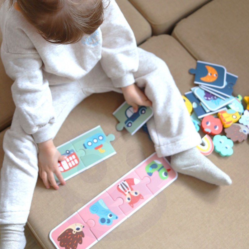 7. Child sitting on beige couch playing with Woopie Green sensory puzzle, matching colorful shapes on puzzle cards