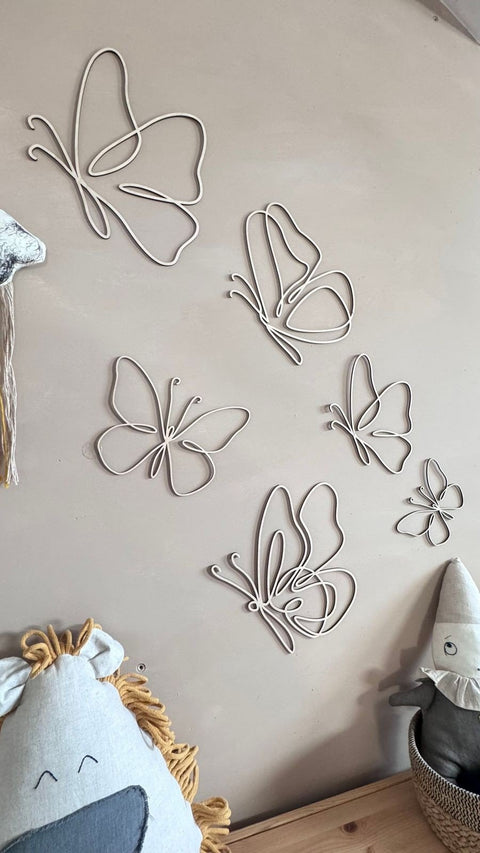 5. Natural plywood butterfly decorations on a wall with plush toys, adding a boho style to a child's room.