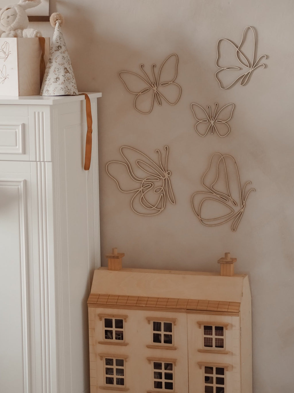 3. Natural plywood butterfly wall decor above a wooden dollhouse in a child's room, enhancing a playful environment.