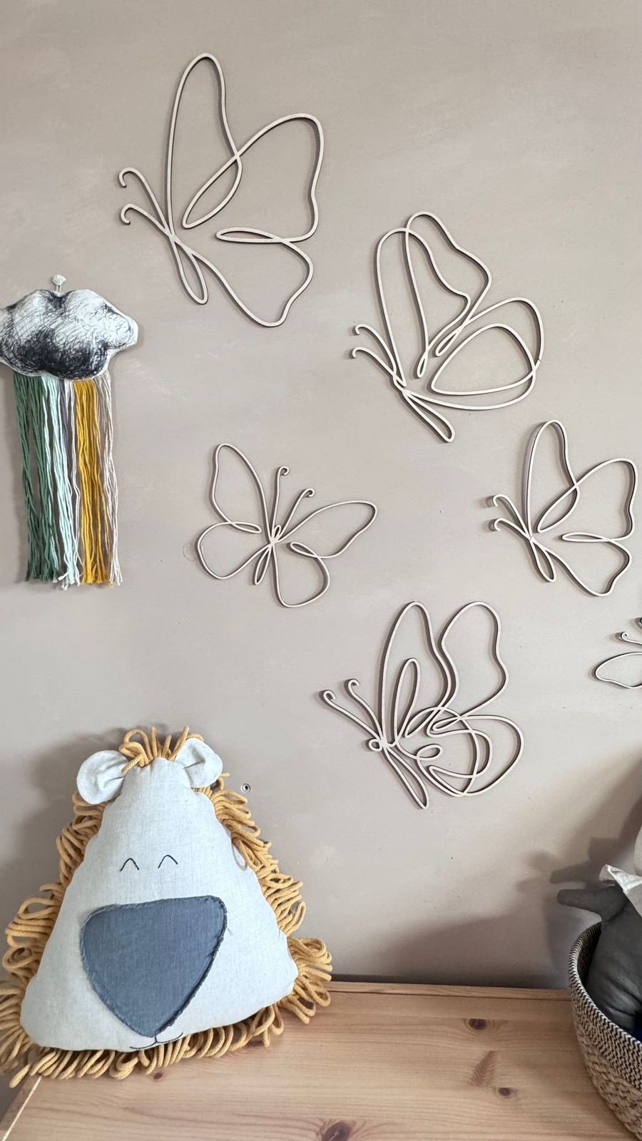 4. Set of six wooden butterflies on a beige wall with plush toys, creating a warm and inviting children's room.