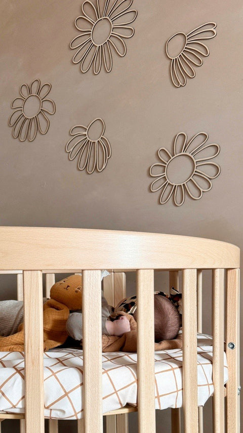 2. Natural plywood daisy wall decorations above a crib in a child's room, adding a cozy and natural touch to the space.