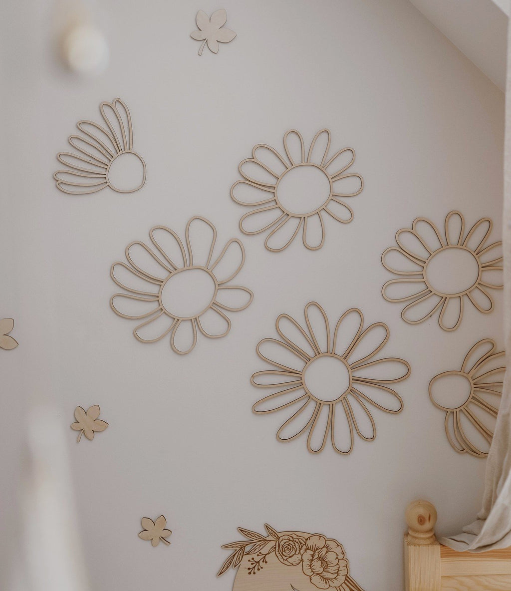 1. Set of six natural plywood daisy wall decorations arranged on a white wall in a child's room, creating a playful and organic atmosphere.