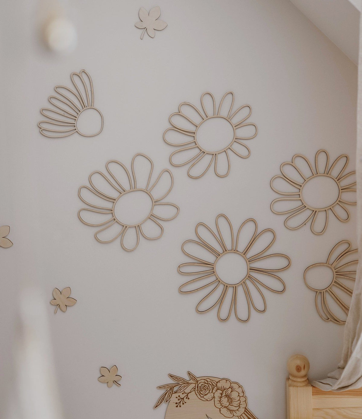 1. Set of six natural plywood daisy wall decorations arranged on a white wall in a child's room, creating a playful and organic atmosphere.