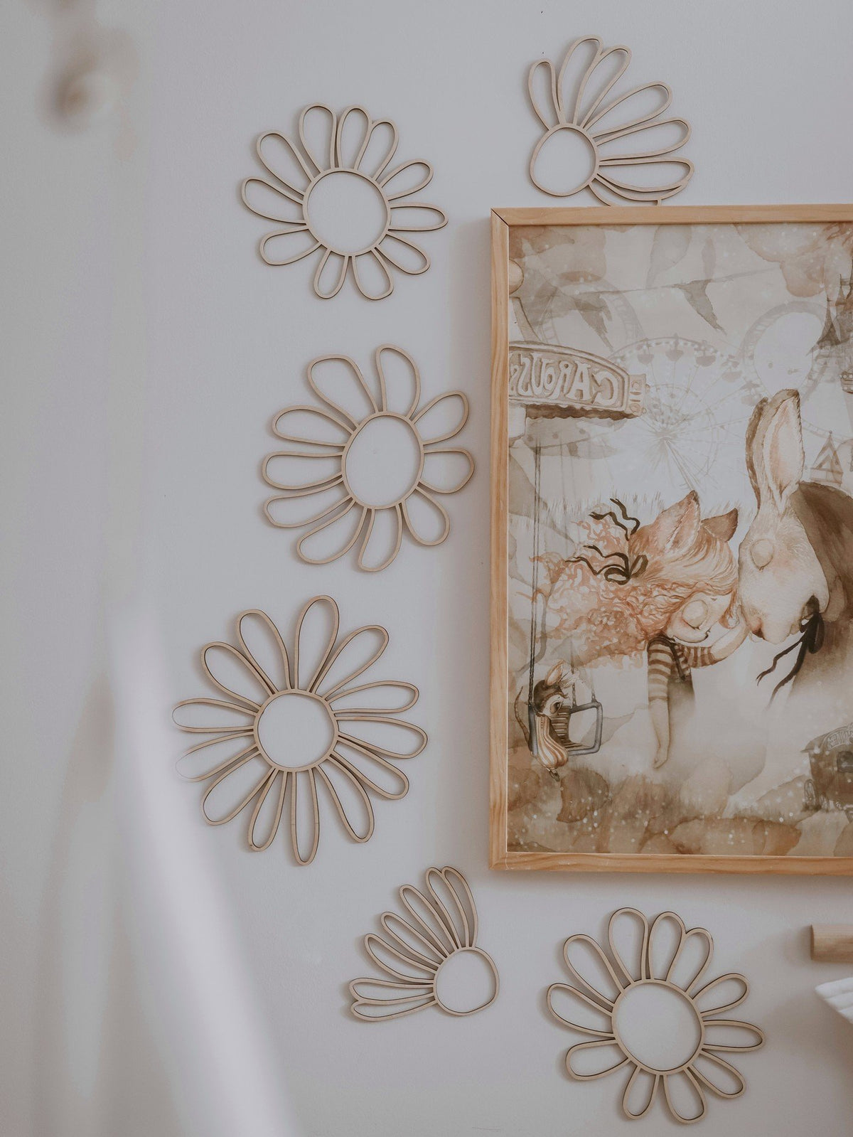 5. Natural plywood daisy wall decorations surrounding a framed artwork in a child's room, adding a subtle and organic accent.