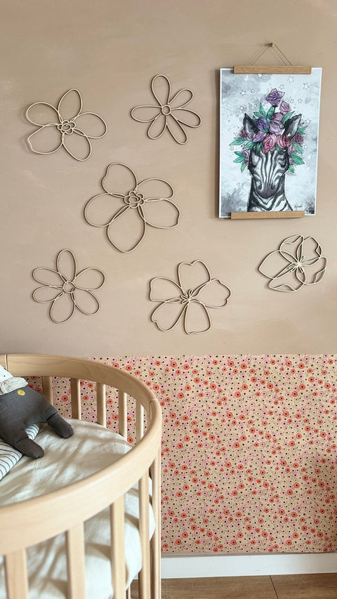 2. Children's room with six wooden flower wall decorations on a beige wall, next to a zebra art print, above a crib with a floral-patterned wall border.