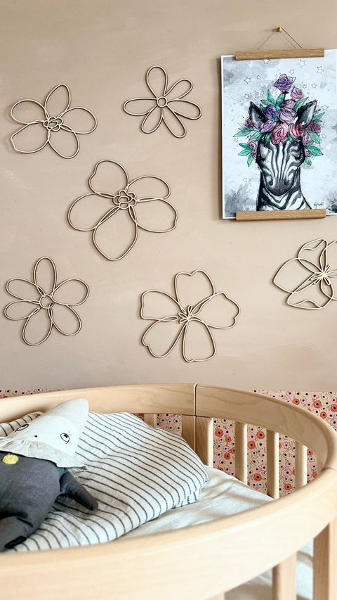 3. Nursery room featuring six wooden flower wall decorations on a beige wall, with a zebra art print and a crib in the foreground.