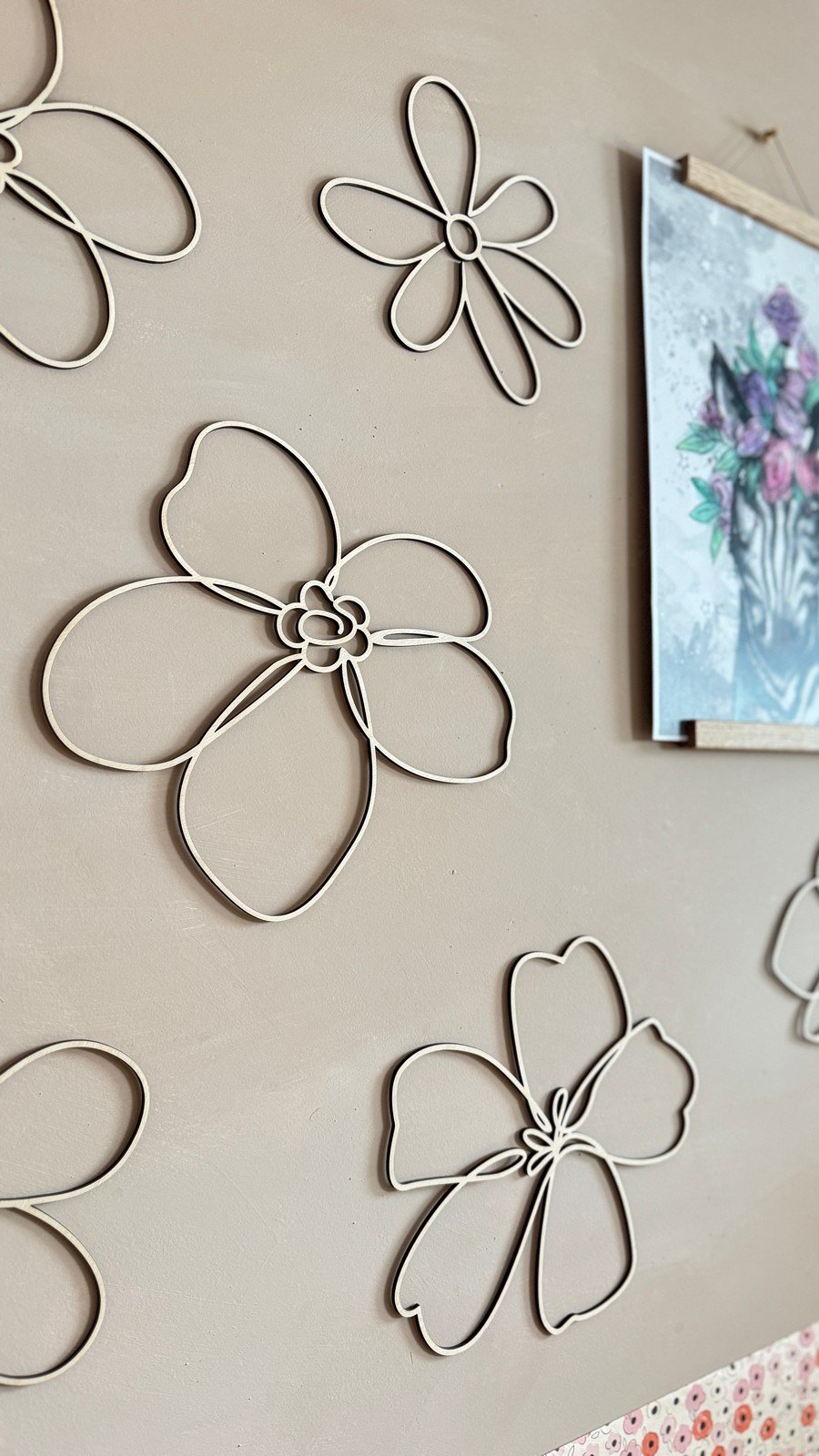6. Close-up of natural plywood flower wall decorations on a beige wall, showing smooth edges and intricate design details.