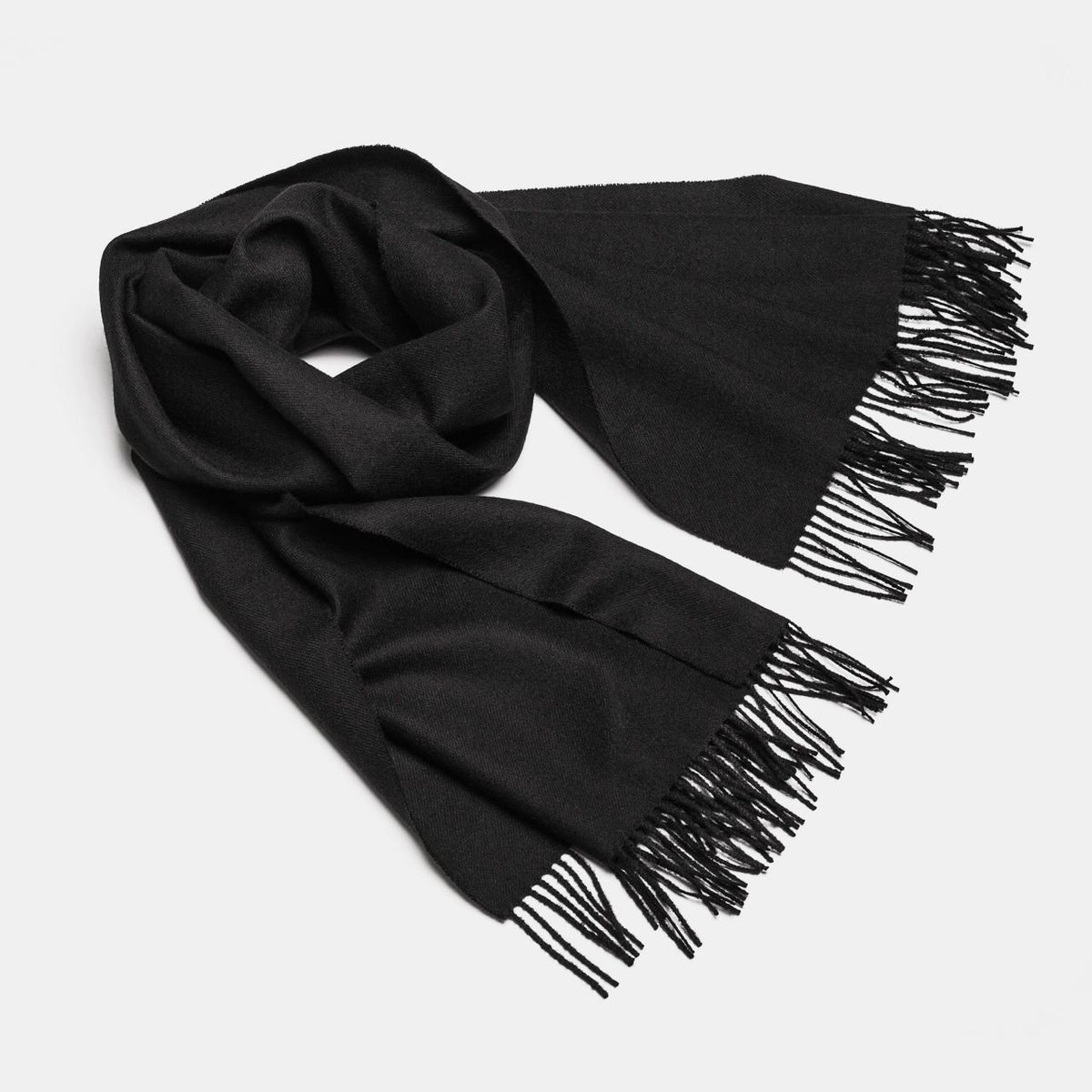 20. Studio shot of Alpaka natural baby alpaca maxi-scarf in black with fringes, displayed in a rolled style
