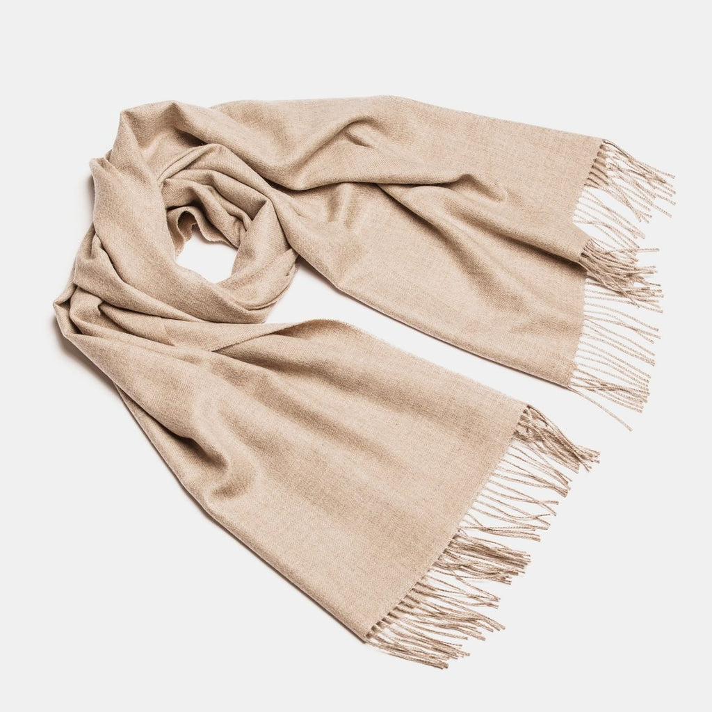 17. Studio shot of Alpaka natural baby alpaca maxi-scarf in beige with fringes, displayed in a rolled style