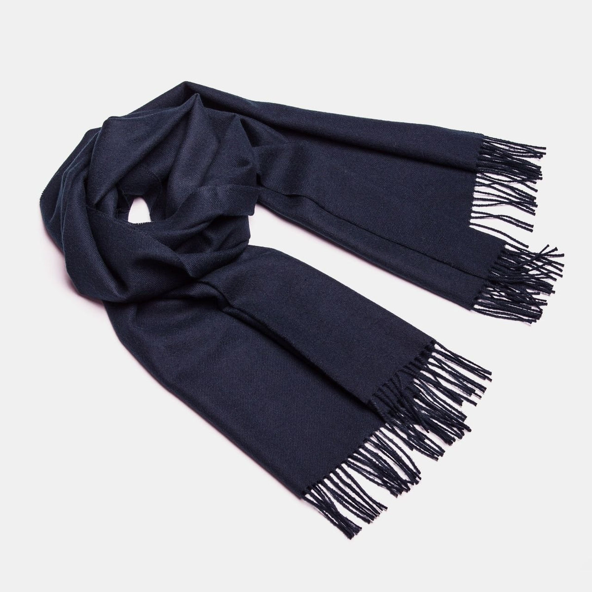 14. Studio shot of Alpaka natural baby alpaca maxi-scarf in navy with fringes, displayed in a rolled style