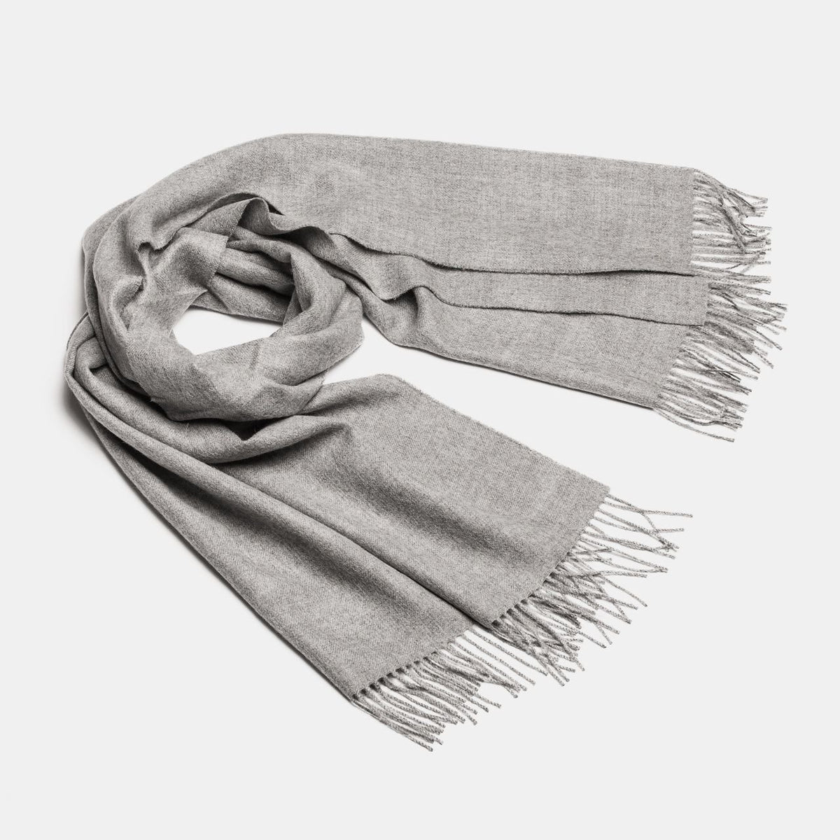 12. Studio shot of Alpaka natural baby alpaca maxi-scarf in grey with fringes, displayed in a rolled style