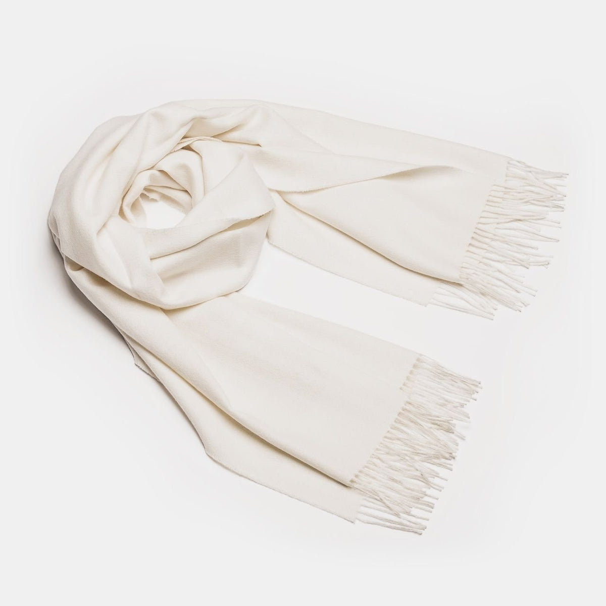 10. Studio shot of Alpaka natural baby alpaca maxi-scarf in cream with fringes, displayed in a rolled style
