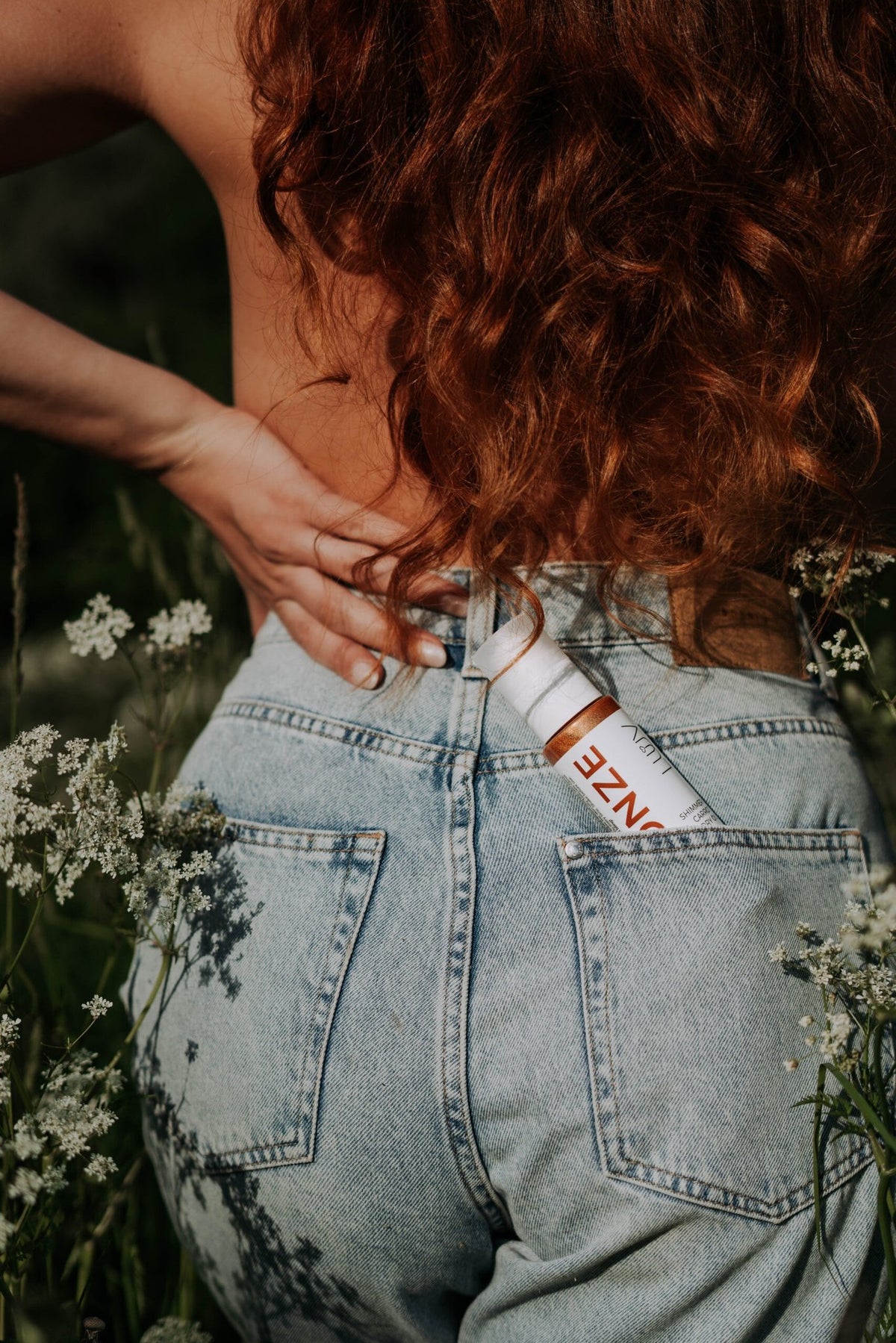 1. LUUV Shimmering Carrot Dry Oil Bronze in back pocket of jeans, outdoor setting