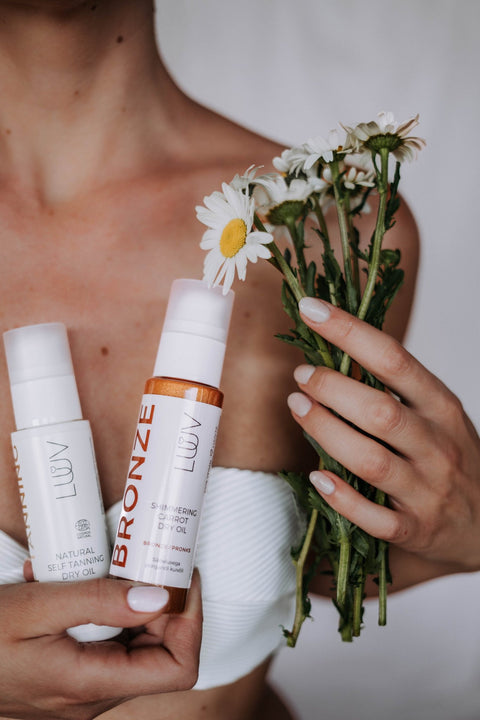 4. Woman holding LUUV Shimmering Carrot Dry Oil Bronze and daisies, close-up