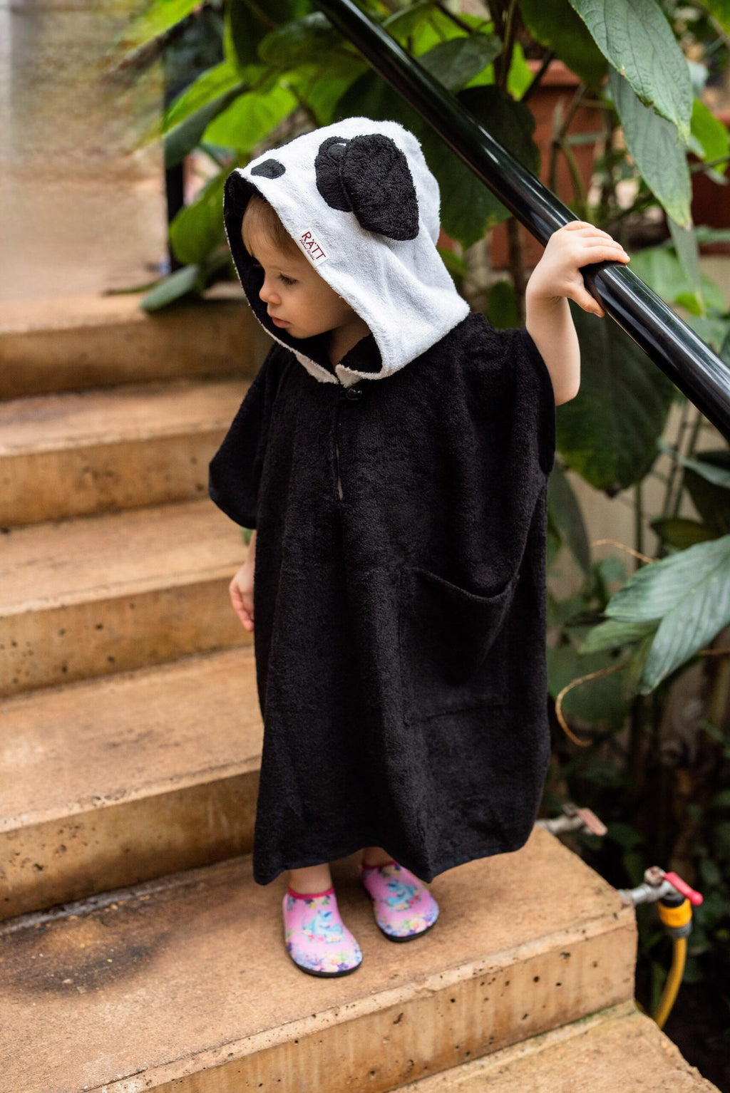 3. Side view of toddler in RÄTT short-sleeve panda poncho, showing brand logo on hood