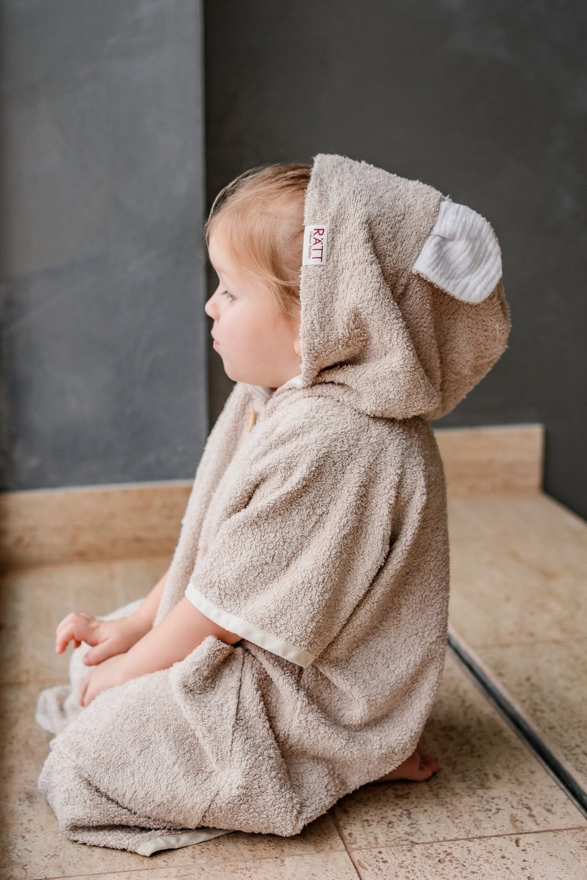3. Side view of toddler in RÄTT short-sleeve poncho TEDDY, showing hood and cozy fit