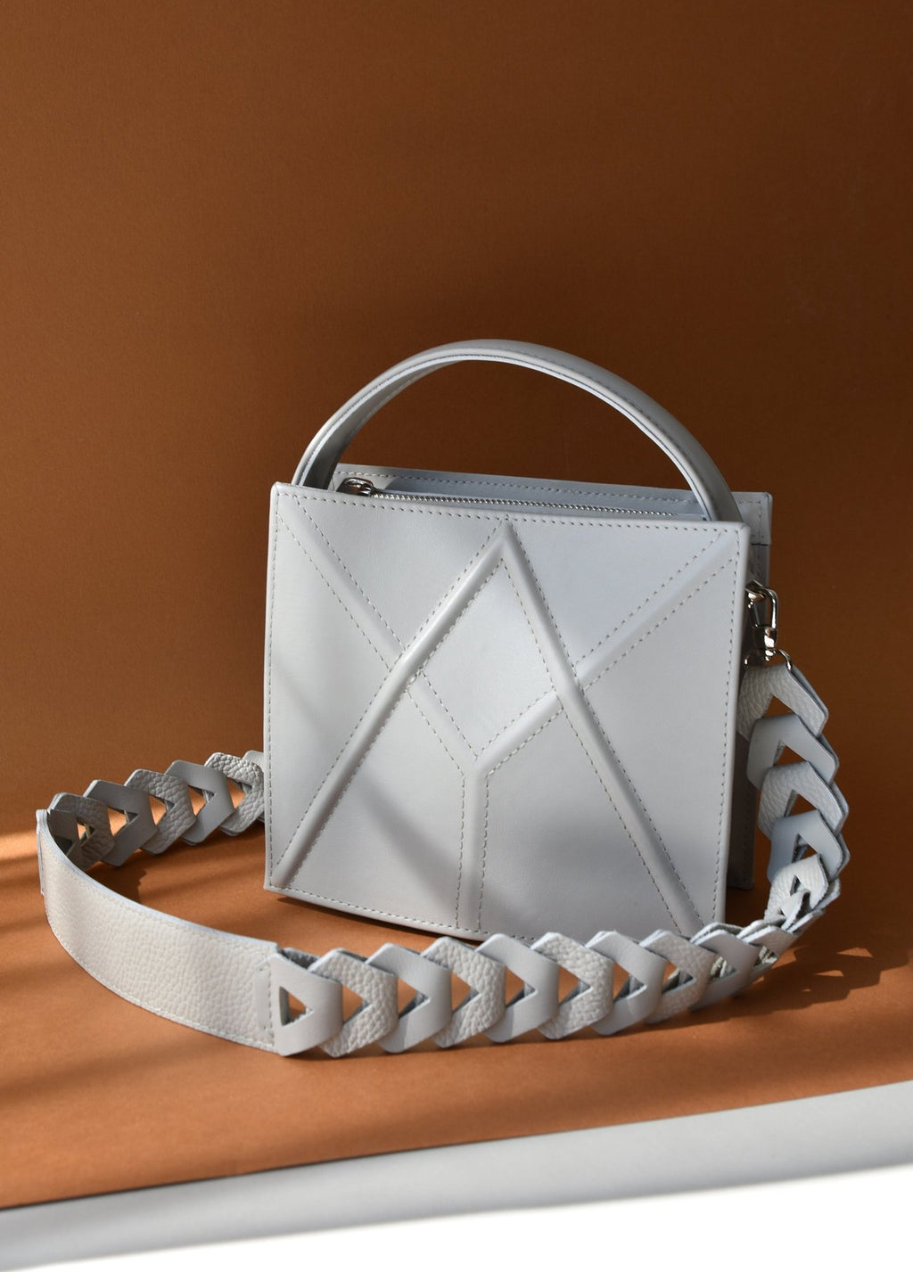 11. Light grey FACET shoulder bag by Gerda Retter Design, shown with a decorative strap in a studio setting