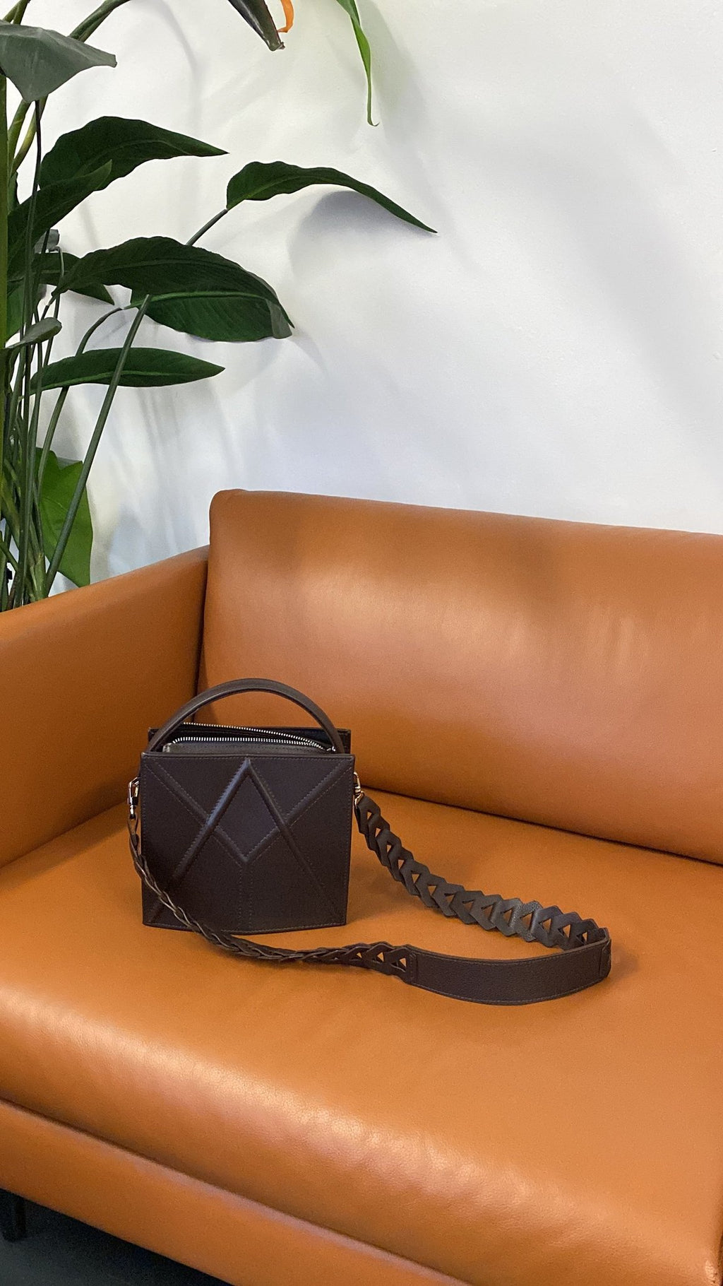 9. Dark brown FACET shoulder bag by Gerda Retter Design, placed on a leather couch in a lifestyle setting
