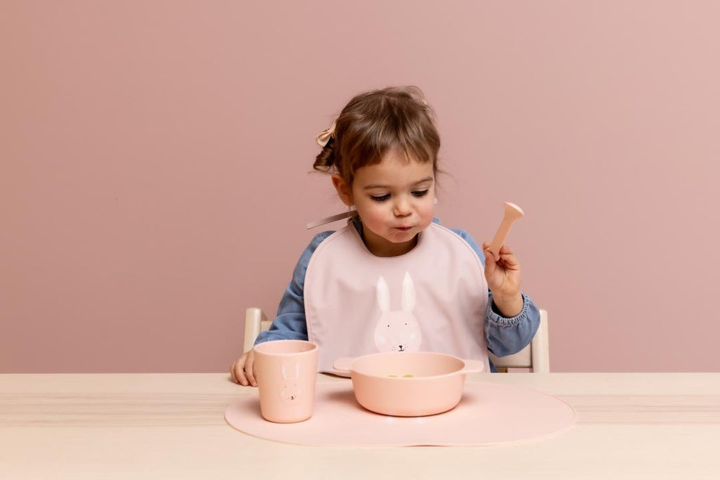 3. Young girl with pink Trixie Baby Mrs. Rabbit silicone bowl and cup at table
