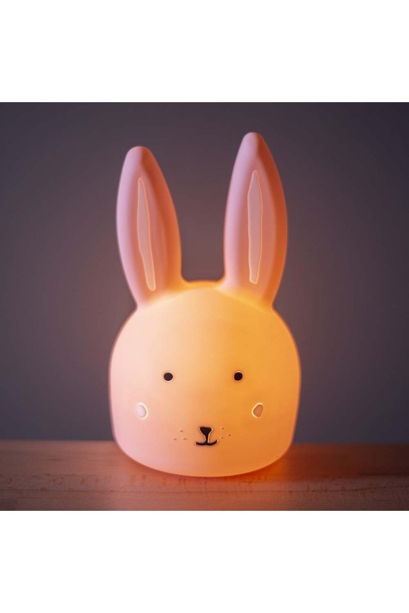 3. Glowing Trixie Baby Mrs. Rabbit silicone night light in dimly lit room showcasing its warm comforting light
