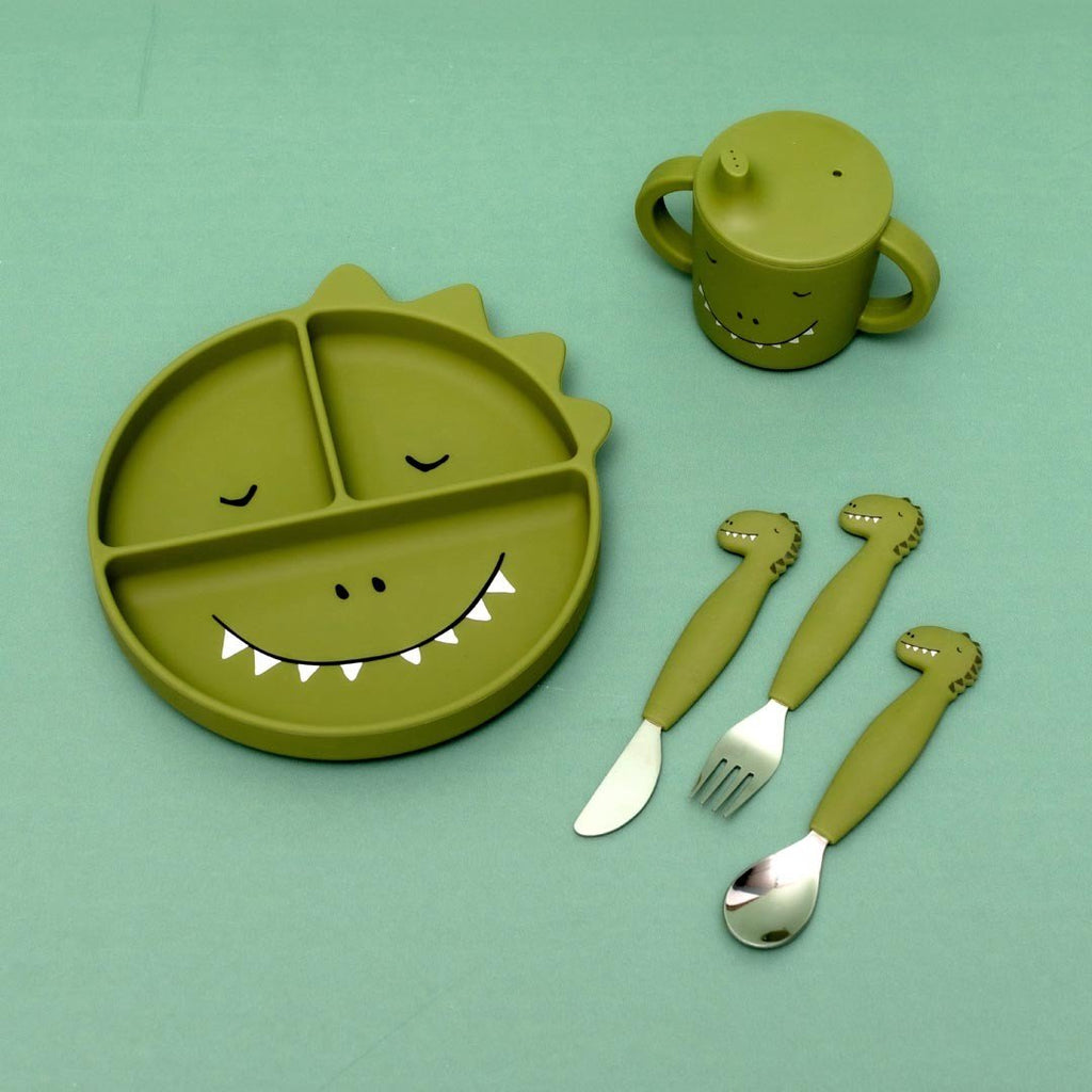 4. Flat lay of green dinosaur-themed tableware set including sippy cup, plate, and utensils on green background