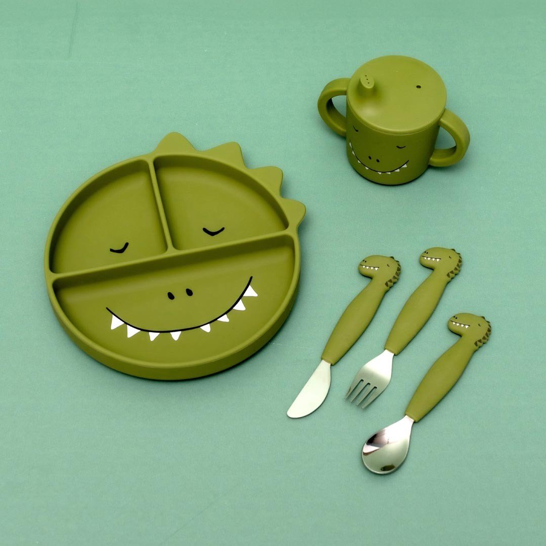 4. Flat lay of green dinosaur-themed tableware set including sippy cup, plate, and utensils on green background
