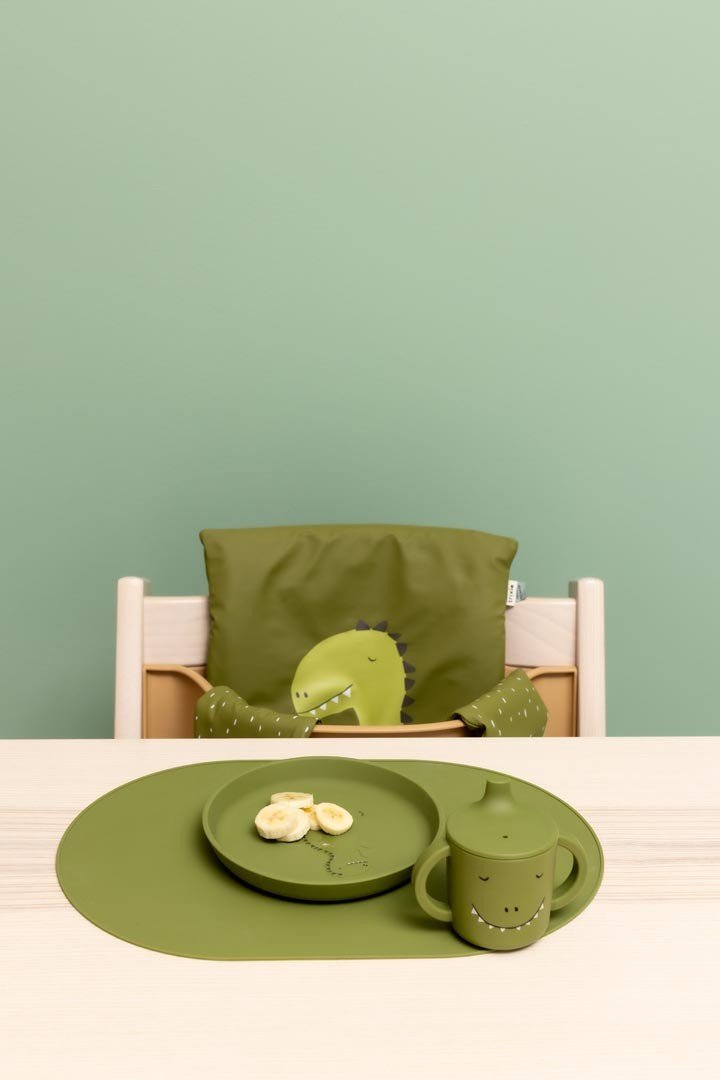 1. Child's dining setup with green dinosaur-themed sippy cup and plate on wooden table