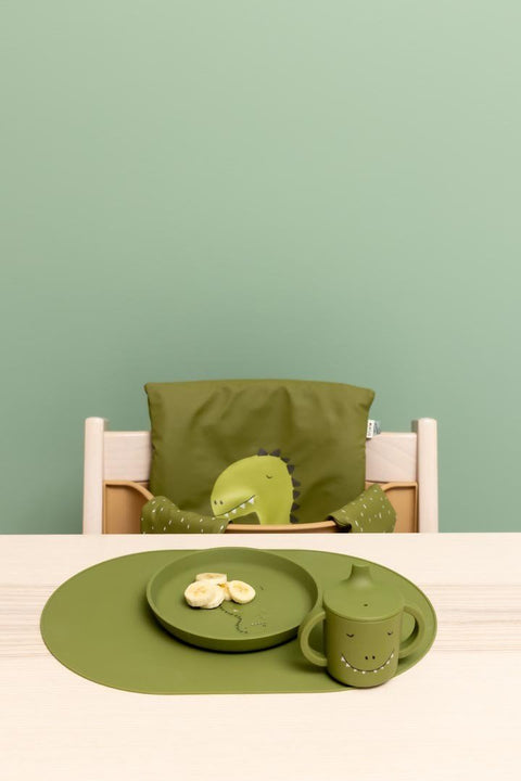 1. Child's dining setup with green dinosaur-themed sippy cup and plate on wooden table