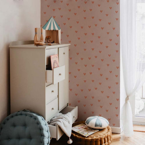 1. Children's room with pink and red heart-patterned wallpaper on beige background, featuring a white dresser and soft furnishings