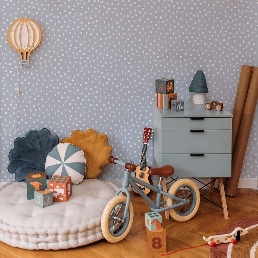 1. Children's room with light blue irregular dots wallpaper, featuring a wooden bike, colorful cushions, and a blue dresser