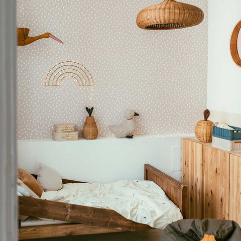 1. Powder pink and white dotted wallpaper in a child's room with wooden furniture and a rainbow decoration