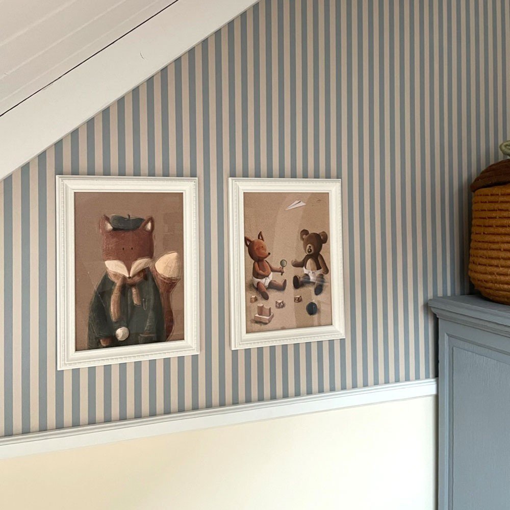 2. Beige and blue striped wallpaper with two framed animal illustrations in a room with slanted ceiling
