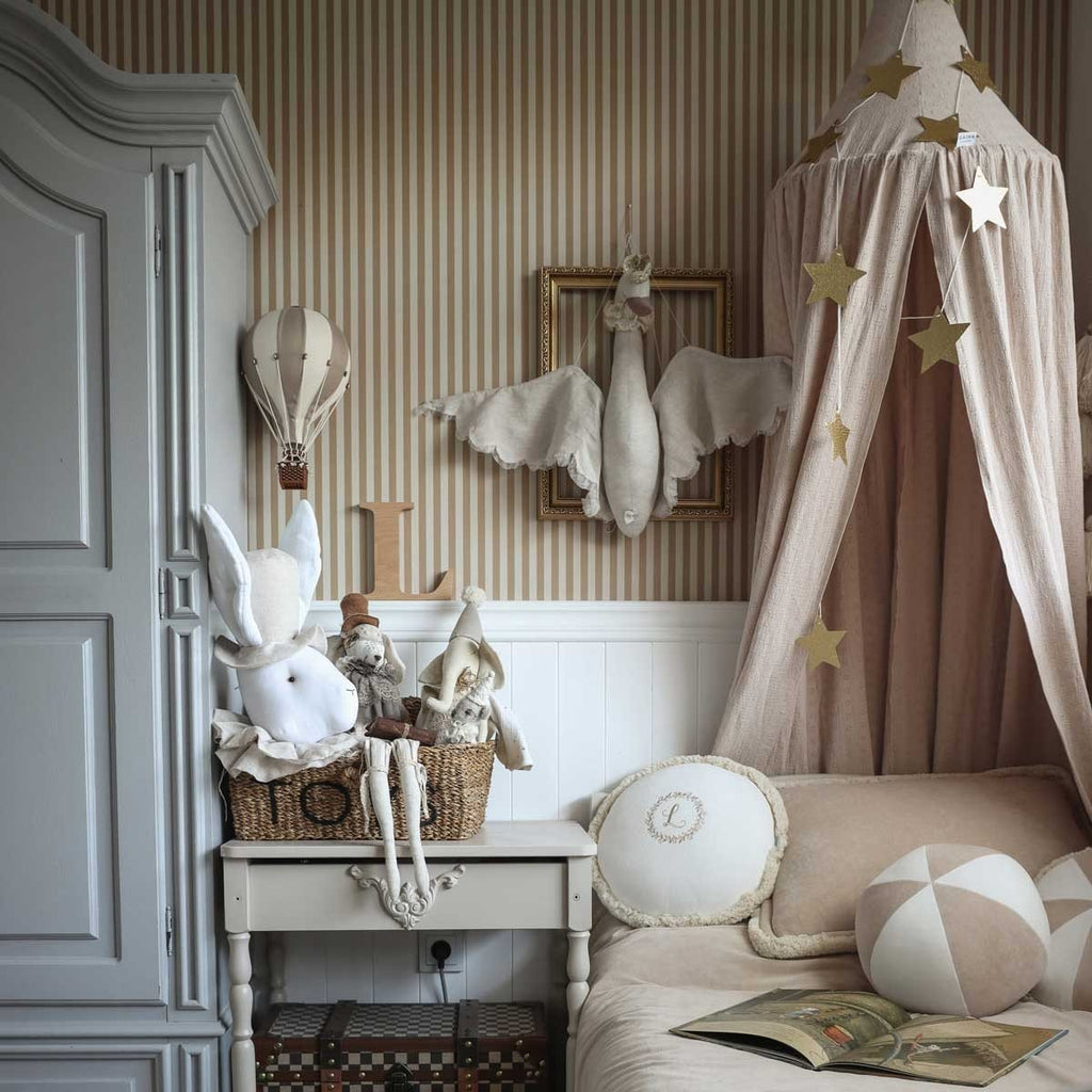 3. Children's room with beige and brown striped wallpaper, featuring a bed with a canopy, plush toys, and decorative elements like a hot air balloon and star garlands
