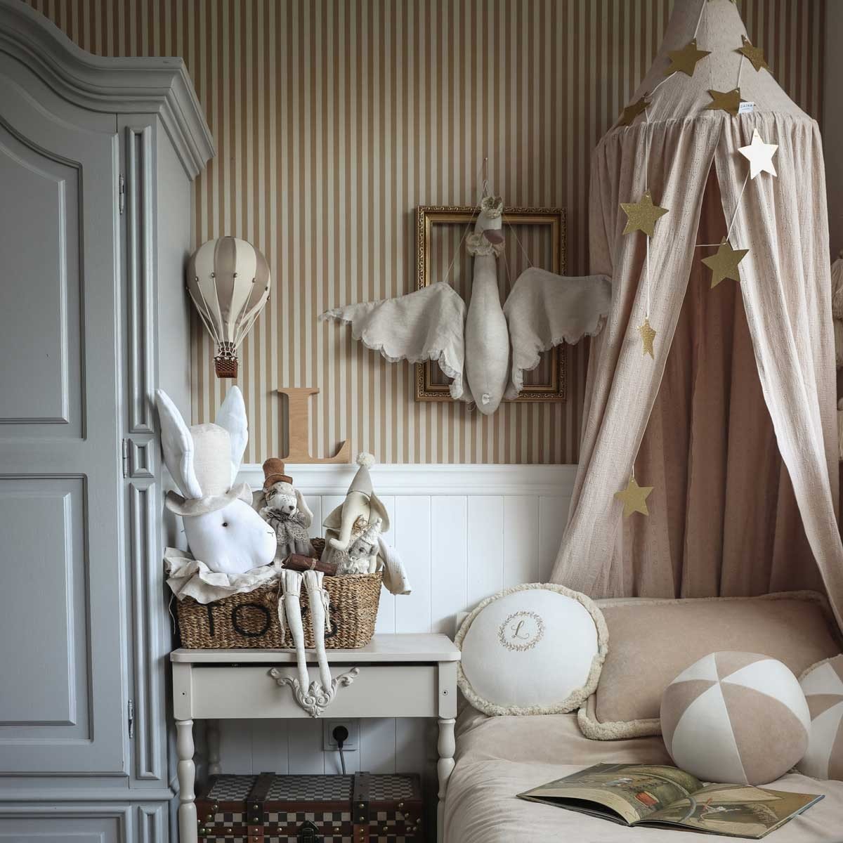 3. Children's room with beige and brown striped wallpaper, featuring a bed with a canopy, plush toys, and decorative elements like a hot air balloon and star garlands